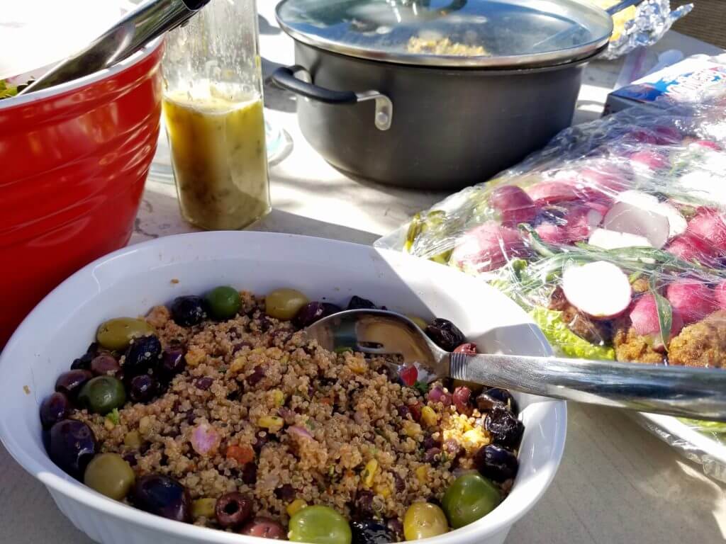 An olive-laden dish next to falafels and radish.